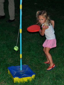 Intent on hitting the swinging ball, a young girl plays in the last few minutes of sunlight before the movie starts. Photo by Brooke Baker